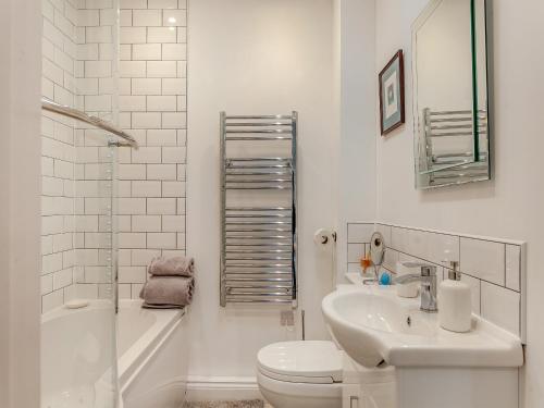 a white bathroom with a sink and a toilet at Barn Cottage in Falfield