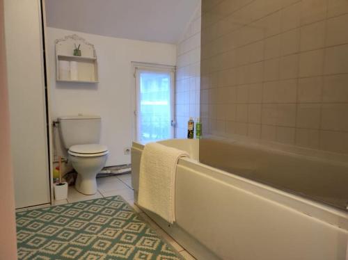 een badkamer met een bad en een toilet bij Nid douillet appart. entier, charme près Paris in Suresnes