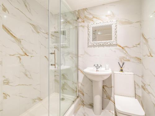 La salle de bains blanche est pourvue d'un lavabo et d'une douche. dans l'établissement The Annexe At Moulton Grange, à Brixworth
