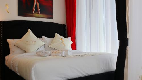Valentina Studio Transit Apartment في أبوظبي: غرفة نوم بسرير ذو شراشف ووسائد بيضاء