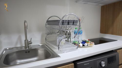 Valentina Studio Transit Apartment في أبوظبي: حوض المطبخ مع رف لتجفيف الأطباق بجوار الحوض
