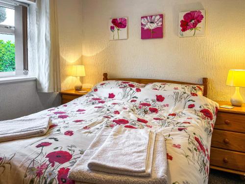 a bedroom with a bed with a floral bedspread at The Corn Store - Uk44693 in Cheadle