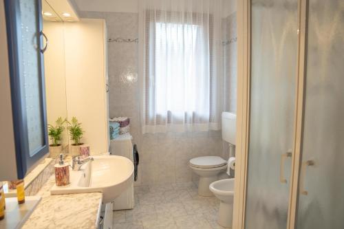 uma casa de banho branca com um lavatório e um WC em Marina's Venice garden em San Giacomo