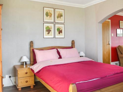 a bedroom with a large bed with pink sheets at The Old School House in Sunk Island