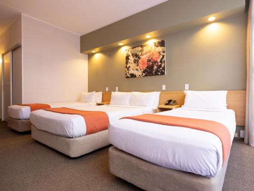 um quarto de hotel com três camas num quarto em Auckland Rose Park Hotel em Auckland