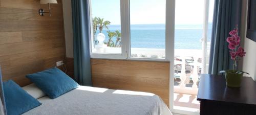 トレモリノスにあるApartamentos Don Pepeのビーチの景色を望むベッドルーム1室(ベッド1台付)が備わります。