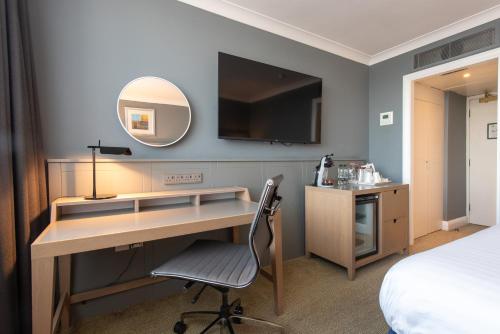 a bedroom with a desk and a bed and a mirror at Holiday Inn - Glasgow Airport by IHG in Paisley