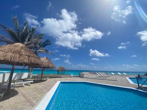 uma piscina com uma palmeira e o oceano em Beach Penthouse with Unique Rooftop Suite & Gorgeous Views em Cancún