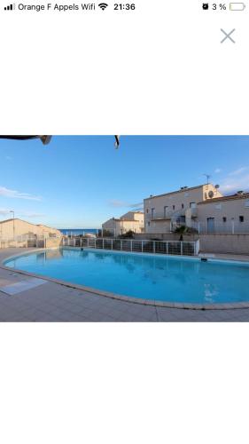 une photo d'une piscine en face de certains bâtiments dans l'établissement MAISON DE VACANCES Avec PISCINE - MER INDIGO- ST PIERRE LA MER- 700m PLAGE, à Saint Pierre La Mer
