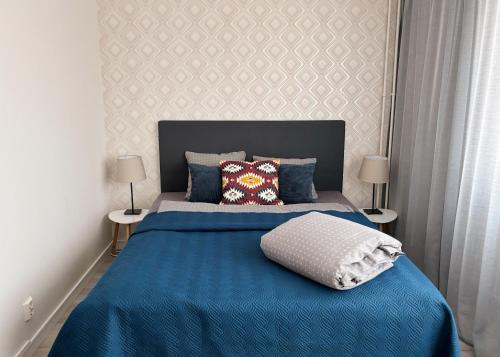 a bedroom with a blue bed with two lamps at Hamina City Apartments in Hamina