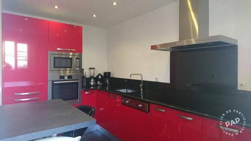 La cuisine est équipée de placards rouges et d'un four avec plaques de cuisson. dans l'établissement Maison OCCHIATANA, à Occhiatana