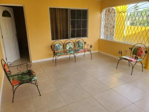 a room with three chairs and a window at Cozy Villa in Old Harbour