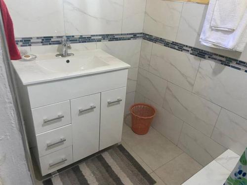 a white bathroom with a sink and a shower at Cozy Villa in Old Harbour
