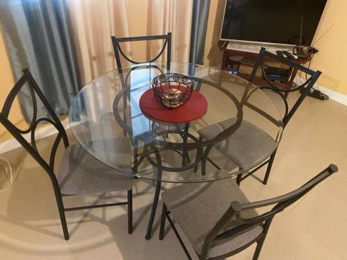 a glass table with chairs and a candle on it at Cozy Villa in Old Harbour