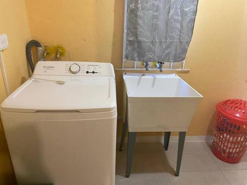 a kitchen with a sink and a washing machine at Cozy Villa in Old Harbour