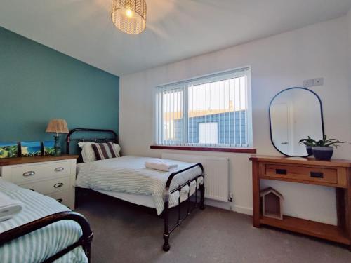 1 dormitorio con 2 camas y espejo en Coastal Bungalow, en Prestatyn