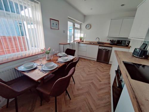 a kitchen with a wooden table with chairs and a dining room at Coastal Bungalow in Prestatyn