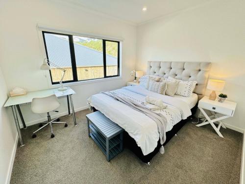 Schlafzimmer mit einem großen Bett, einem Schreibtisch und einem Fenster in der Unterkunft Zen hideaway in Aotea in Porirua