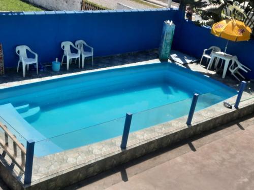 una piscina con agua azul y sillas frente a una pared azul en Flats Divina Ilha, en Ilha Comprida