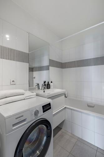 une buanderie blanche avec un lave-linge. dans l'établissement Confort et style Proche de Paris, à Asnières-sur-Seine