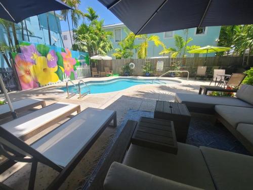 a pool with tables and chairs and an umbrella at 6 Bedroom 6 Bath Guesthouse on Duval Street in Key West