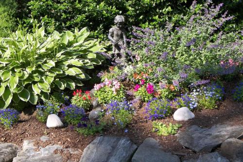 a garden with flowers and a statue in the middle at Cedar Crest Inn in Camden