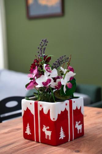 a red and white flower pot on a table with flowers at Apartament 47 in Gjirokastër