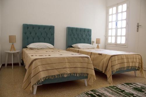 a bedroom with two beds with blue headboards and a window at BEAU SÉJOUR hébergement et spa 