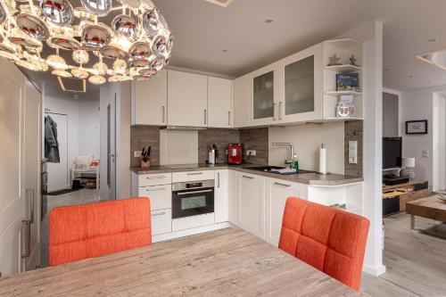 eine Küche mit weißen Schränken und orangefarbenen Stühlen in der Unterkunft Ferienwohnung Krabbe in Wangerooge