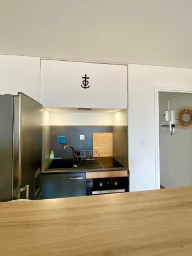 une cuisine avec un évier et un réfrigérateur en acier inoxydable dans l'établissement Appartement T2 vue exceptionnelle CARNON-PLAGE, à Carnon-Plage