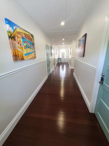 a hallway with white walls and wood floors and paintings on the walls at Duval Street Suite overlooking Duval with parking and pool in Key West