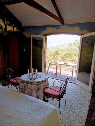 a bedroom with a bed and a table and chairs at Chalés do Cachoeirão in Visconde De Maua