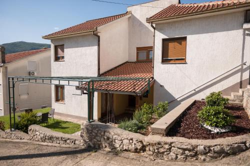 ein weißes Haus mit einer Veranda und einem Gebäude in der Unterkunft Apartman Emina in Mostar