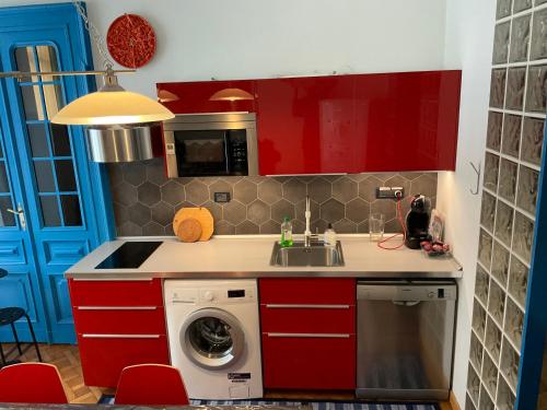 - une cuisine avec des placards rouges et un lave-linge dans l'établissement NONPERTUTTI PIAZZA CASTELLO Senior e famiglie TOP, à Turin