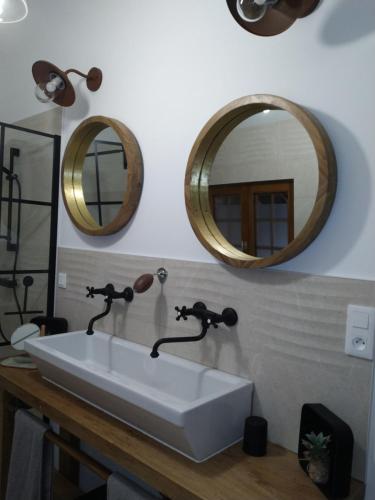 baño con lavabo blanco y 2 espejos en A la maison du bonheur, en Lanty-sur-Aube