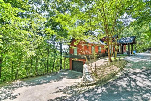 a red house with a garage in the woods at Pet-Friendly Branson Area Home Hot Tub, Game Room in Reeds Spring