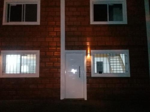 un edificio de ladrillo con una puerta blanca y dos ventanas en Cabaña Davis en Sierra de la Ventana