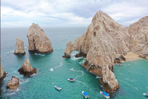 a group of boats in the water next to some rocks at Marina Junior suite in Cabo San Lucas