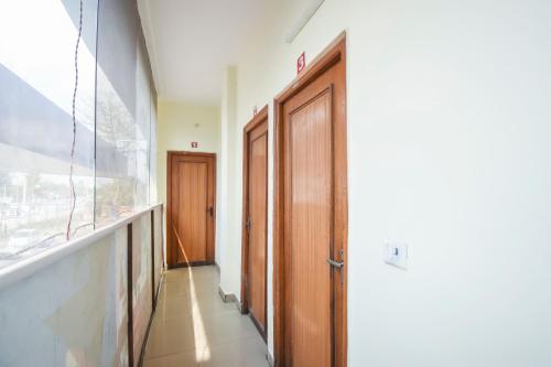 a hallway with two wooden doors and a window at Hotel Lazeez in Karnāl