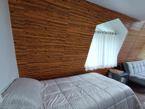 a bedroom with wooden walls and a bed and a chair at Vallecito Lodge in Muyurina