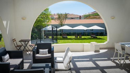 an outdoor patio with chairs and tables and an archway at Espinho Vintage - Alojamento de Charme in Espinho