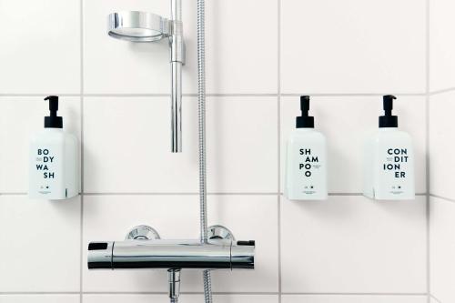 Baño con lavabo y botellas de jabón en la pared en Scandic Kristiansand Bystranda en Kristiansand