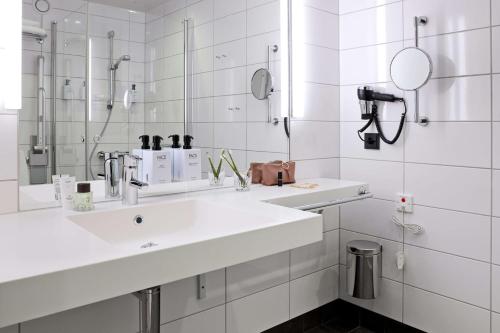 a white bathroom with a sink and a mirror at Scandic Continental in Stockholm