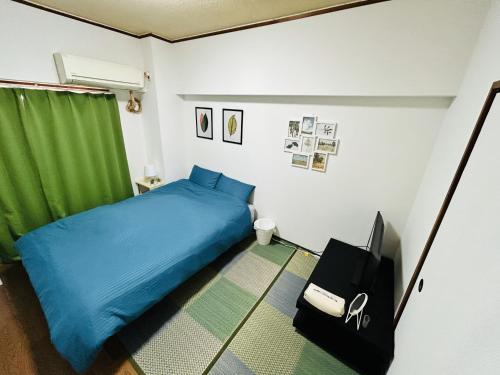 1 dormitorio con 1 cama azul y TV en GUEST HOUSE GREEN BASE HAKATA en Fukuoka