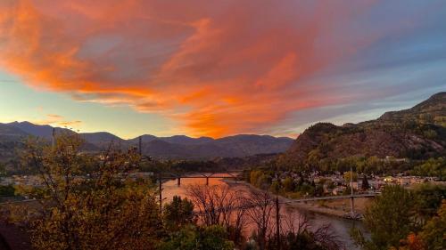 a sunset over a river with a bridge and mountains at Comfy Home in Trail