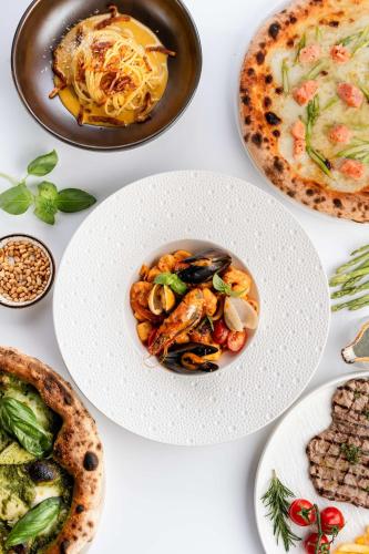 a table with plates of food and pizza at Radisson Blu Hotel, Dubai Media City in Dubai