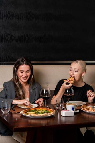 two people sitting at a table eating pizza at Radisson Blu Hotel, Dubai Media City in Dubai