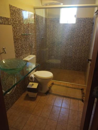 een badkamer met een toilet en een glazen douche bij viladasararas in Alto Paraíso de Goiás