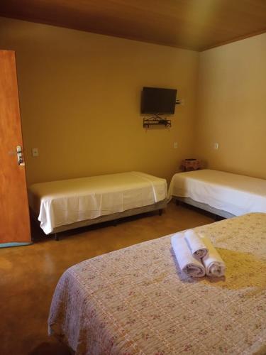 een hotelkamer met 2 bedden en een televisie bij viladasararas in Alto Paraíso de Goiás