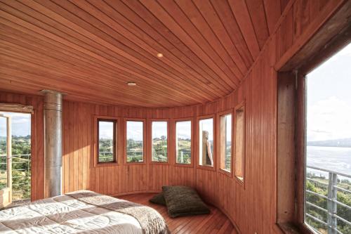 Casa Barco Chiloe في Quilquico: غرفة نوم مع سرير في غرفة مع نوافذ